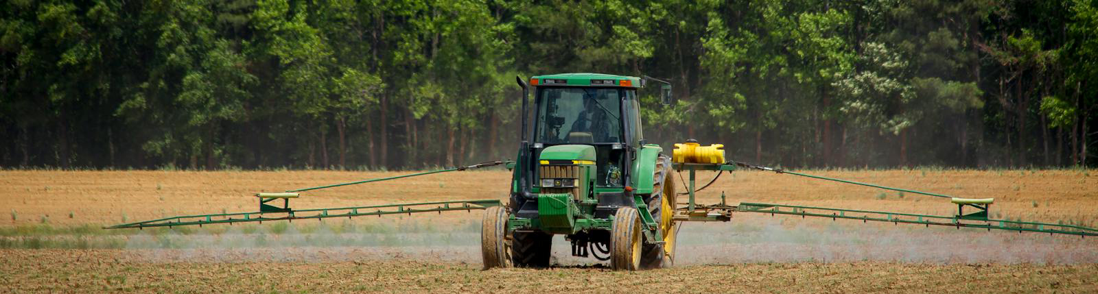 A tractor in a field, spraying pesticides